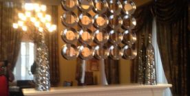 Mirror ornament hung on a wall mirror above fireplace.